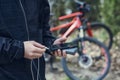 A tourist charges a smartphone with a power bank on the background of a bicycle in nature