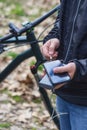 A tourist charges a smartphone with a power bank on the background of a bicycle in nature