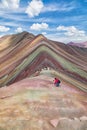 Tourist climbs in the foreground of the Rainbow Mountains at an altitude of 5000 meters