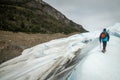 The tourist climbs the glacier with a stick. Shevelev.