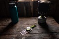 Tourist compass, water bottle and gas burner. Travel set. Old wooden table in the hut. Royalty Free Stock Photo