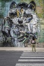 a tourist contemplates the artwork of big raccoon by street artist bordalo ii, street art, urban nature, in the district of belem