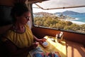 A tourist continues his hobby, rocks painting, with the beautiful background of the Greek island of Paros