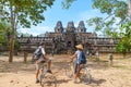 Tourist couple cycling around Angkor temple, Cambodia. Ta Keo building ruins in the jungle. Eco friendly tourism traveling, toned Royalty Free Stock Photo