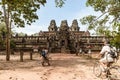 Tourist couple cycling around Angkor temple, Cambodia. Ta Keo building ruins in the jungle. Eco friendly tourism traveling, toned Royalty Free Stock Photo