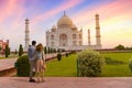 Tourist couple enjoy view of the Taj Mahal Agra at sunrise with moody sky