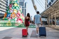 tourist couple pull travel luggage in city