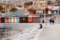 Tourist couple sit by the bay with colourful storehouse at Neuchatel pier