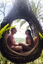 A tourist couple sitting on a large bird nest on a tree at Bali island Royalty Free Stock Photo