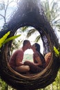 A tourist couple sitting on a large bird nest on a tree at Bali island Royalty Free Stock Photo