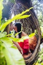 A tourist couple sitting on a large bird nest on a tree at Bali island Royalty Free Stock Photo