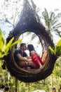 A tourist couple sitting on a large bird nest on a tree at Bali island Royalty Free Stock Photo