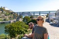 Tourist couple with sunglasses on posing for a photo in front of an arch bridge Maria Pia in Porto