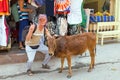 Tourist with a cow in front of a clothing shop in Laxman Jhula India Royalty Free Stock Photo