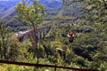 A tourist crosses over a long cable car over a mountain and a forest across the Tiara River Royalty Free Stock Photo