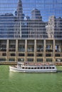 Tourist cruise tour boat on Chicago canal with reflective building showing blue sky and skyscrapers Royalty Free Stock Photo