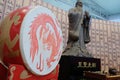 A red dragon is drawn against the background of a statue of Confucius