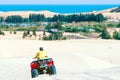 Tourist enjoy riding the quad bike or powerful fast off-road four-wheel drive ATVs at white sand dunes