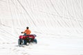 Tourist enjoy riding the quad bike or powerful fast off-road four-wheel drive ATVs at white sand dunes