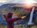 Tourist enjoying dramatic view of high waterfall in Iceland