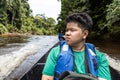 Tourist enjoying scenic nature view of Tembeling river cruise with lush rainforest foliage at Taman Negara National Park