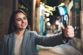 Tourist female blogger shooting video for social media with digital camera. Smiling  woman taking selfie videovlog on light night Royalty Free Stock Photo