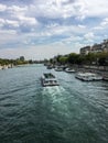 A tourist ferry on the Seine leaves a wake on a summer day under a cloudscape