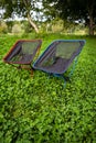 Tourist foldable folding chair for two - red and blue stands in the park, outdoor recreation.