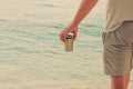 Tourist food for outdoor activities. Metal thermo cup in hand on coastline. Enjoy a tasty drinks during trips. Sea background