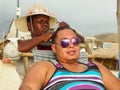 Tourist getting his hair braided by a local woman in Canoa beach, Ecuador