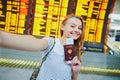 Tourist girl in airport, taking funny selfie with passport Royalty Free Stock Photo