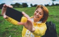 Tourist girl on background green grass taking photo selfie on mobile smart phone, person looking on camera gadget technology, blog Royalty Free Stock Photo