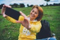 Tourist girl on background green grass taking photo selfie on mobile smart phone, person looking on camera gadget technology, blog Royalty Free Stock Photo