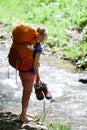 a tourist girl with backpack and boots crosses a mountain river barefoot Royalty Free Stock Photo