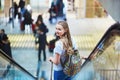 Tourist girl with backpack and carry on luggage in international airport, on escalator