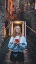 Tourist girl blonde with glasses and camera using mobile phone traveling evening old historical city Europe, young hipster plans Royalty Free Stock Photo