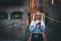 Tourist girl blonde with glasses uses smartphone traveling through old historical city Europe, young hipster plans walk