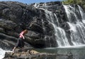 Tourist girl carefully walking near the waterfall
