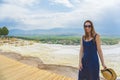 Tourist girl in dress with hat in Natural travertine pools and terraces in Pamukkale. Cotton castle in Turkey. Woman in pamukkale.