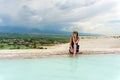 Tourist girl in dress with hat in Natural travertine pools and terraces in Pamukkale. Cotton castle in Turkey. Woman in pamukkale.