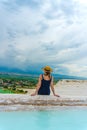 Tourist girl in dress with hat in Natural travertine pools and terraces in Pamukkale. Cotton castle in Turkey. Woman in pamukkale.