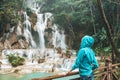 Tourist girl enjoy in Kuang Si waterfall, Luang Prabang, Laos. Young woman have fun and happy sightseeing with nature at Tat Kuang