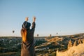 A tourist girl in a hat admires hot air balloons flying in the sky over Cappadocia in Turkey. Impressive sight. Royalty Free Stock Photo