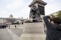 tourist girl poses with lion statue on trafalgar square in london with national gallery in the background Royalty Free Stock Photo