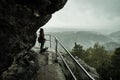 Tourist girl with a puppy dog looking at the misty fog mountains from viewpoint of Bastei in Saxon Switzerland, Germany