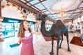 Tourist girl rubbing funny camel sculpture in Dubai Mall