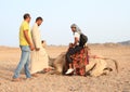 Tourist girl saddling camel for ride