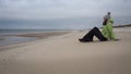 Tourist girl sitting on the Curonian Spit sandy beach Nida, Lithuania. Royalty Free Stock Photo