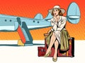 Tourist girl sitting on a suitcase, travelling by plane