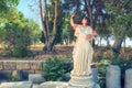 A tourist girl stands behind a statue without a head and points to the side with a hand gesture Royalty Free Stock Photo